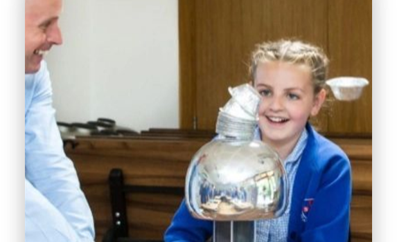 A pupil laughing as her hair stands up on a Van de Graaff generator demonstration