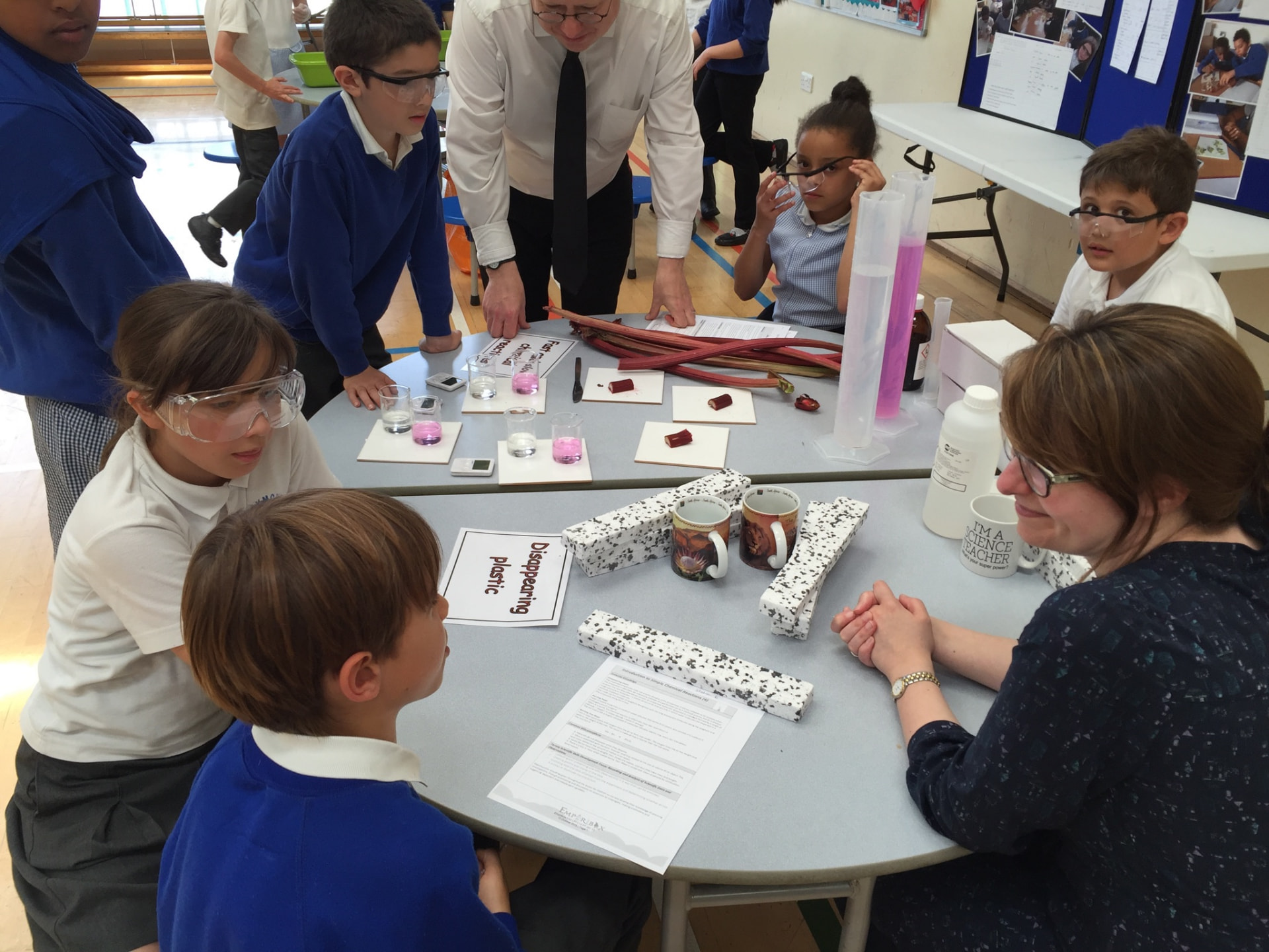 Primary pupils in safety goggles investigating materials with their teachers during a chemistry lesson