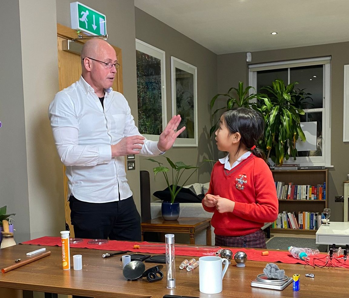 An educator demonstrating science equipment to a pupil at a classroom table