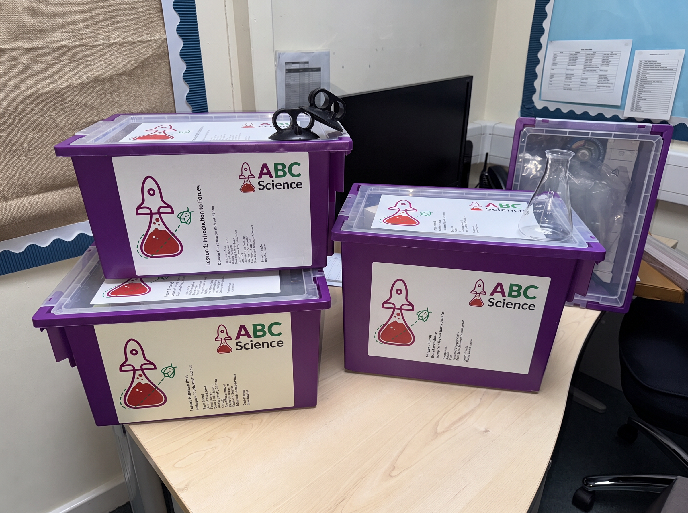 Three purple science equipment boxes with ABC Science logos, a flask and suction cups